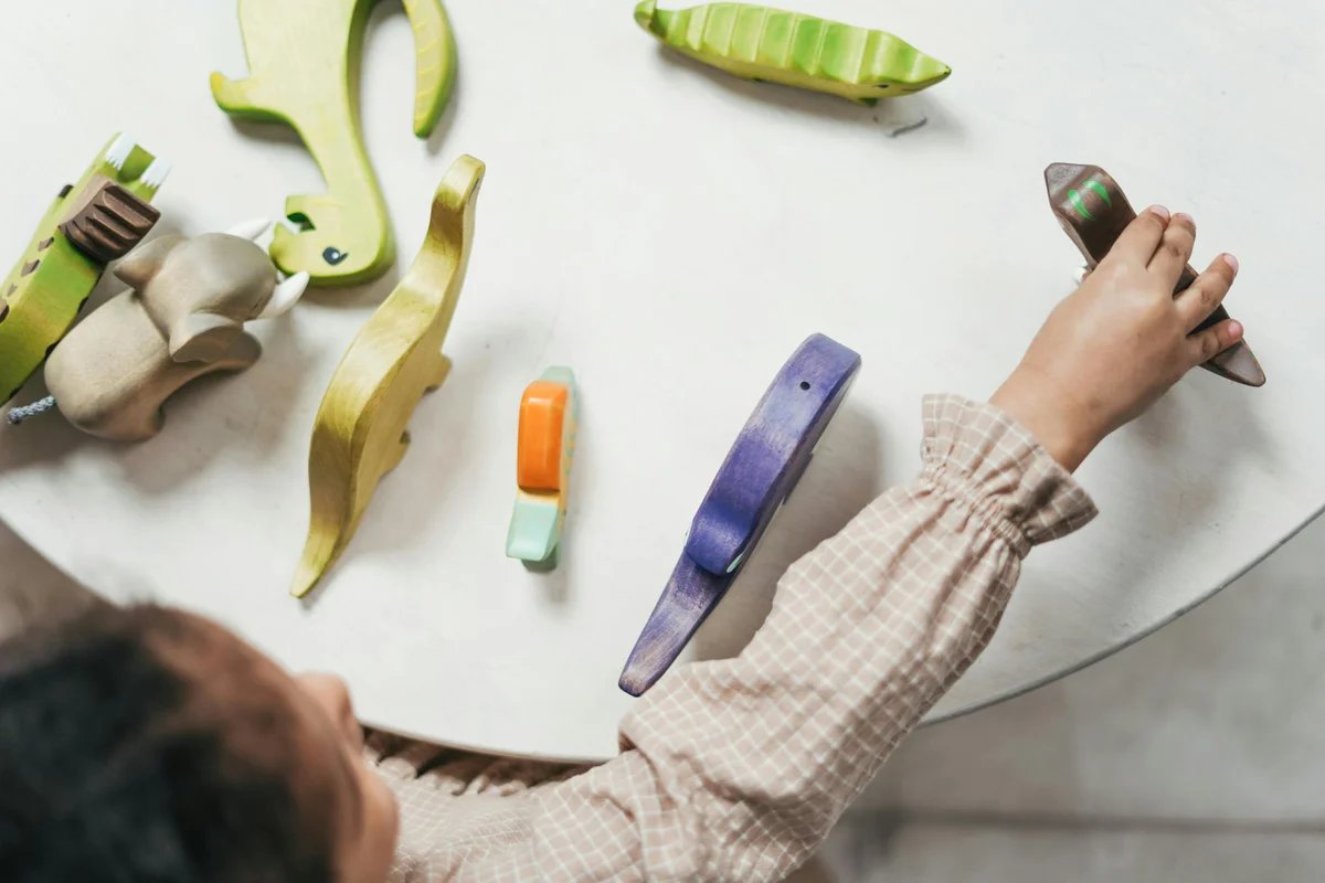 Child playing with colourful wooden toys during play-based speech therapy