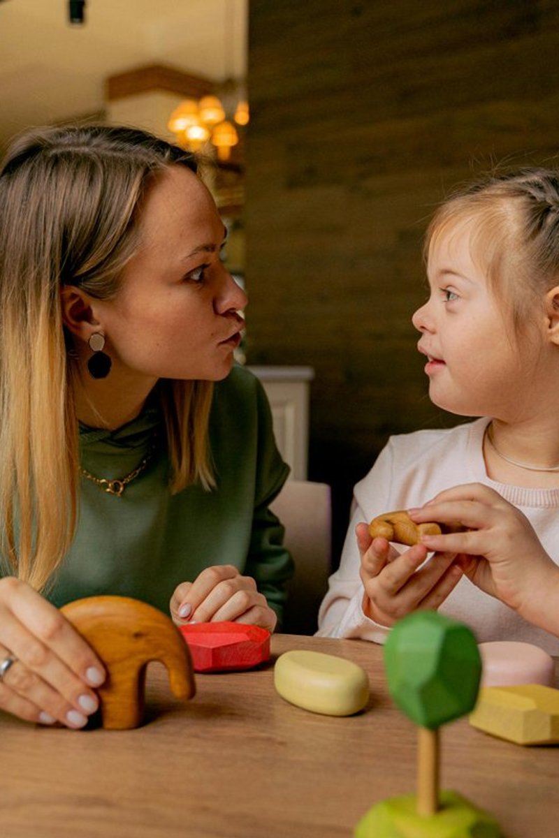 Speech pathologist working face-to-face with a child on communication skills using developmental toys during a therapy session