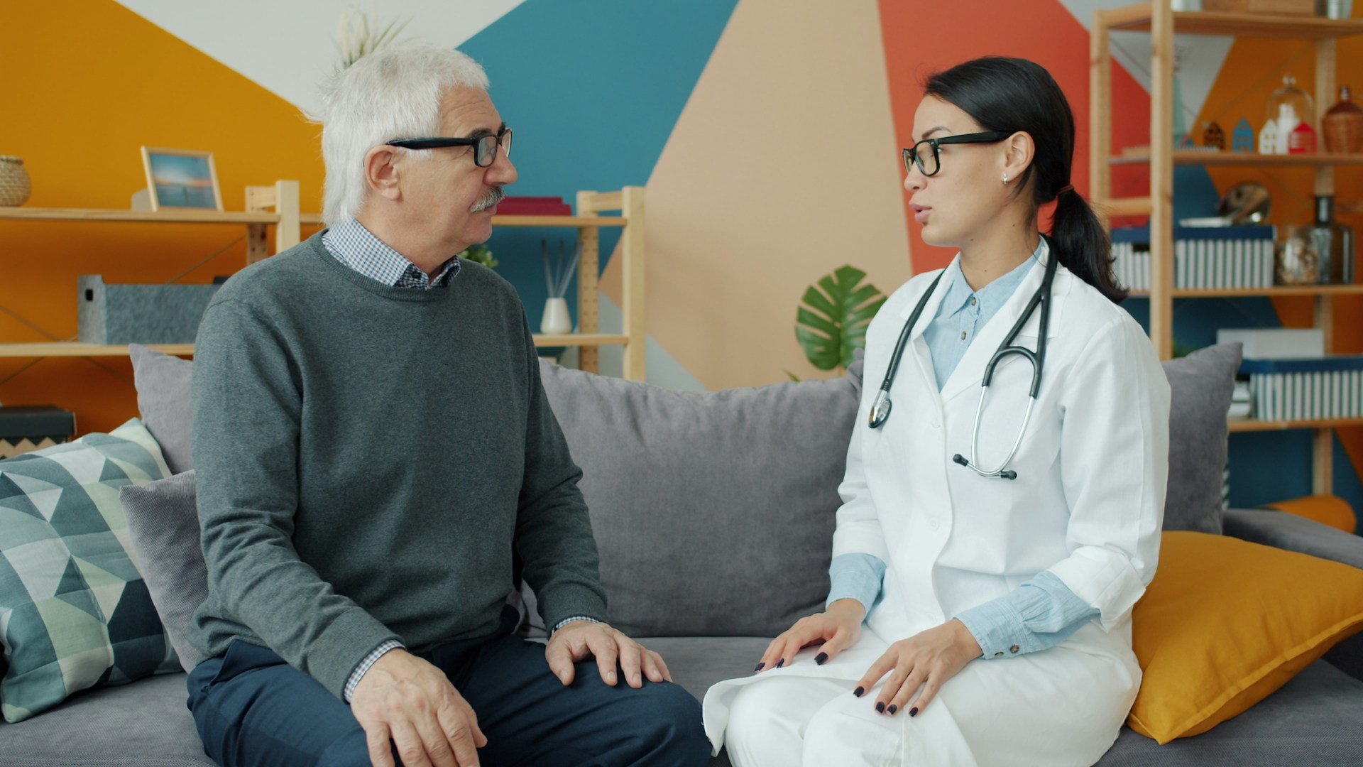 Speech pathologist providing dementia speech therapy to an older man during a home visit