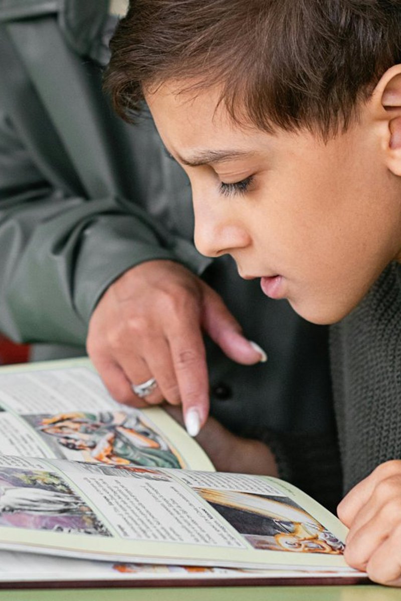 Child receiving reading support from an adult during a literacy assessment consultation