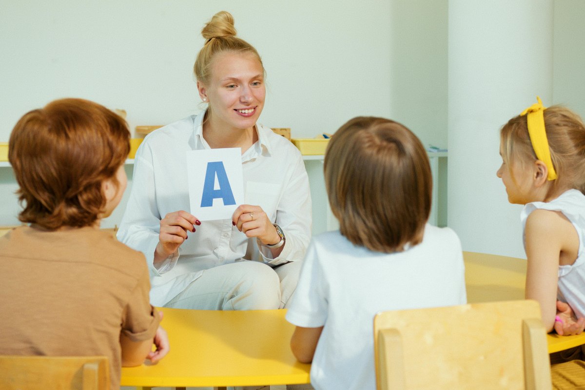 Speech pathologist teaching letter recognition to children during a literacy assessment activity