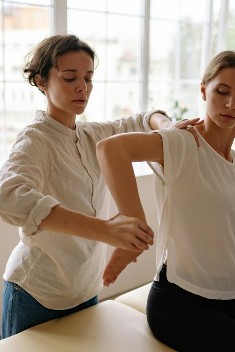 Occupational therapist guiding an NDIS participant through a funded therapy session focused on upper limb mobility