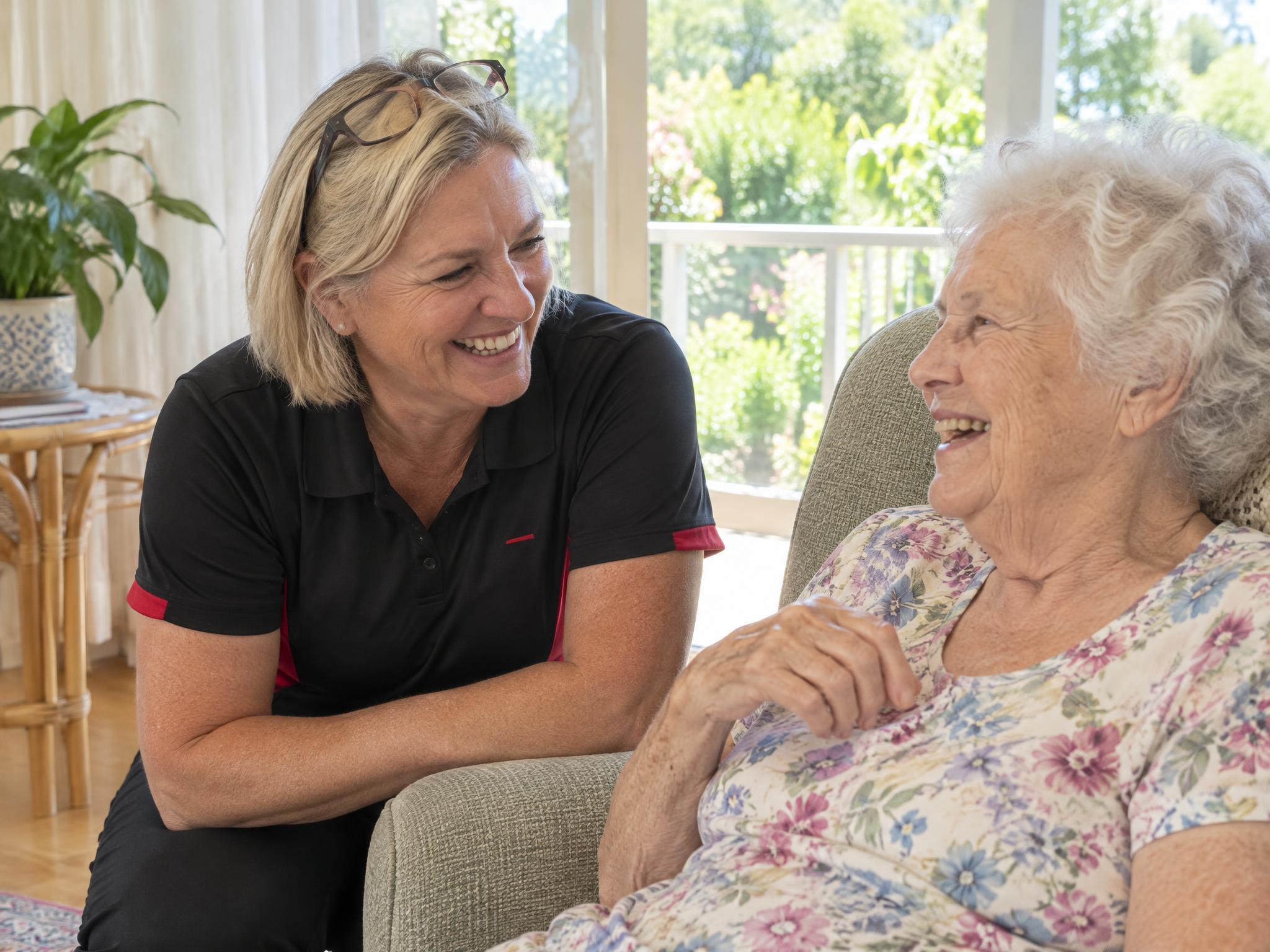 Occupational therapist laughing with an older woman in her armchair during a home safety visit