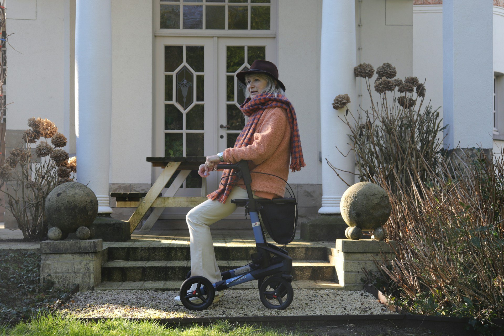 Older woman using a walking frame at her home entrance, part of occupational therapy Brisbane home mobility and safety assessments.