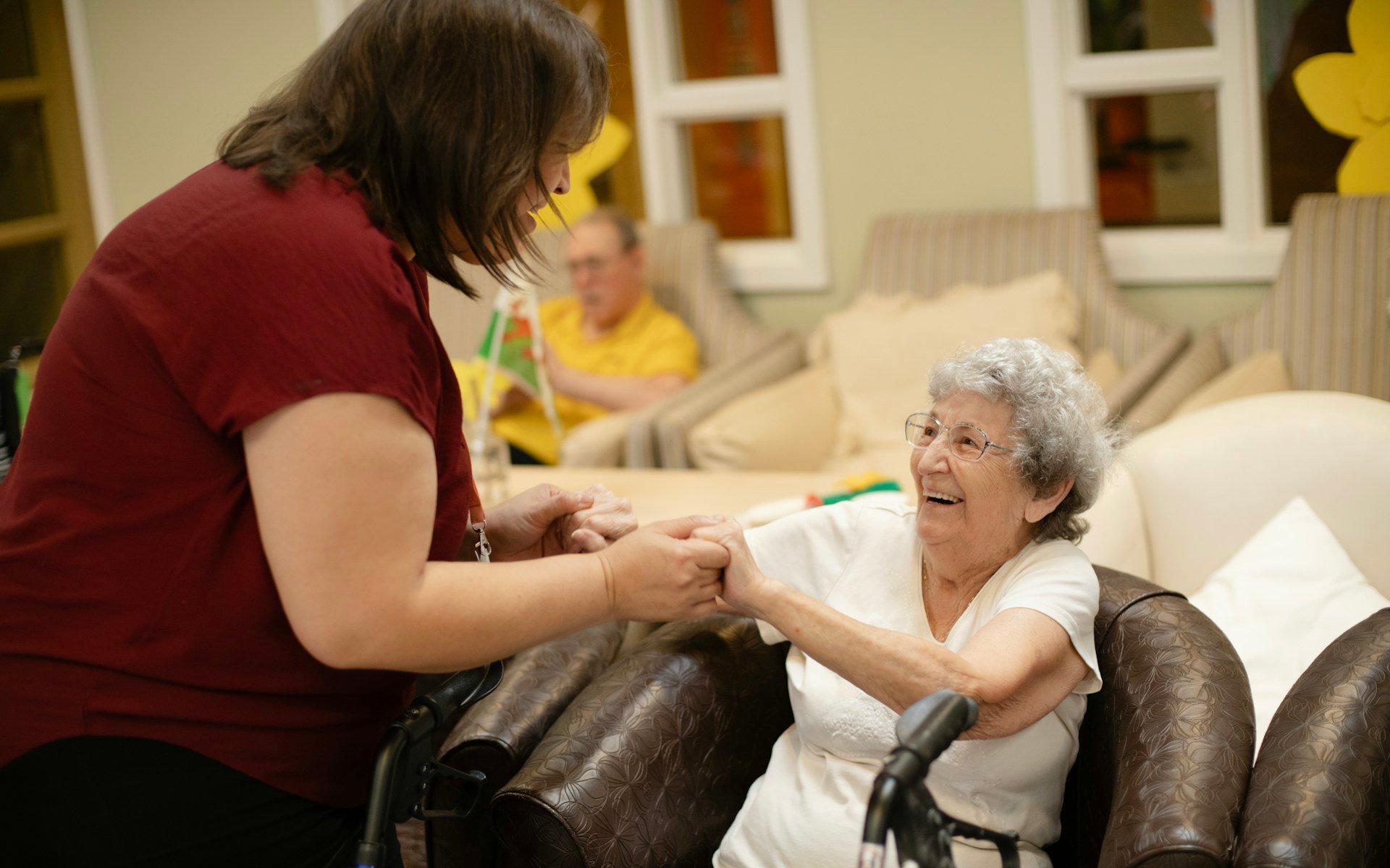 Occupational therapy Gold Coast mobility support, a therapist helping an older woman stand safely with a walker nearby at home
