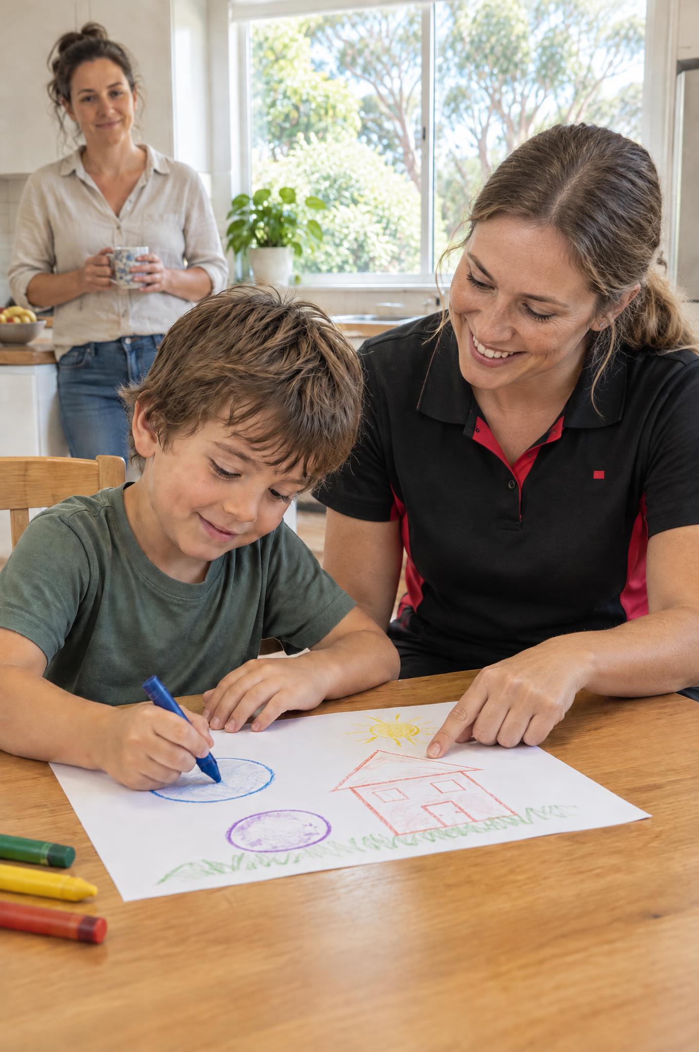 Paediatric occupational therapist helping a young boy draw shapes at the kitchen table while his mum watches