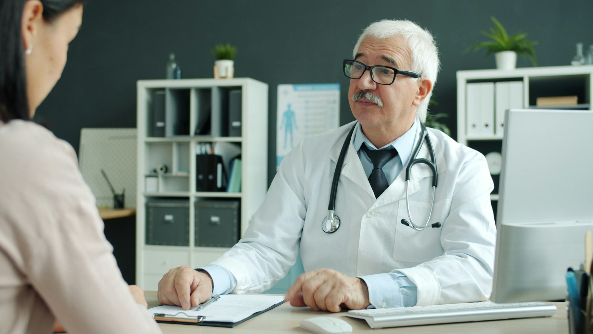 Health professional talking with a client across a desk during a friendly consultation