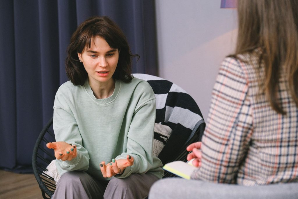 Young woman talking openly with a psychologist during a counselling session in a calm, softly lit room