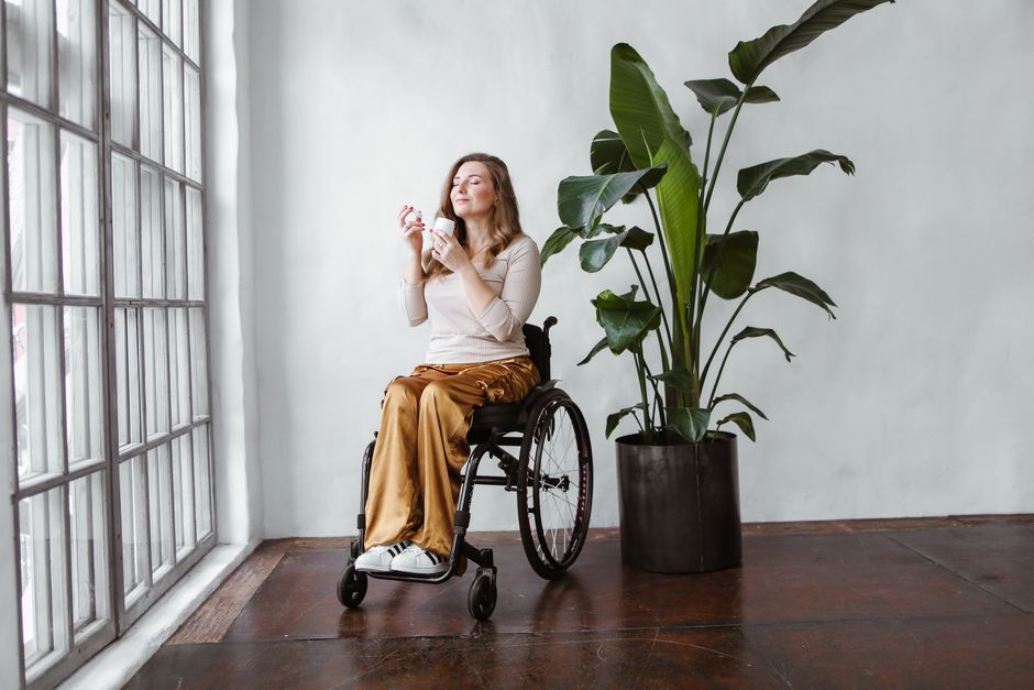 Woman using a wheelchair at home beside a large window, an example of SDA housing that supports independent living