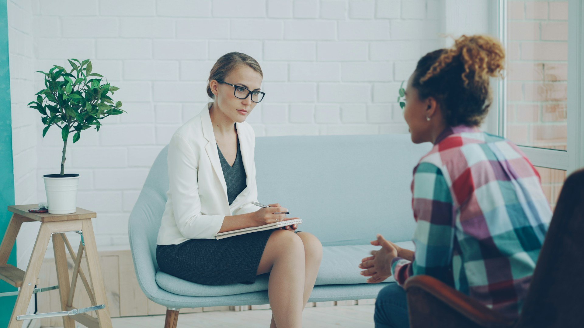 Therapist listening and taking notes with an adult client during a one on one communication session